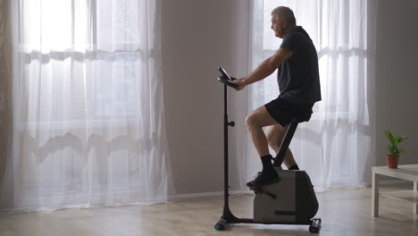 sporty-training-on-stationary-bicycle-middle-aged-man-is-spinning-pedals-exercise-for-health-of-cardiovascular-system-keeping-fit